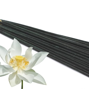 Op de afbeelding: Een bundel zwarte en groene wierookstokjes met een witte lotusbloem op de voorgrond.