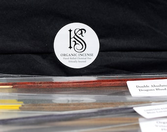 May include: A selection of incense sticks in a clear plastic packet. The sticks are in various colours, including red, yellow, and brown. A white label reads "Double Absolute Dragons Blood." A round sticker says "Organic Incense".