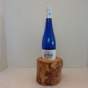 Puede incluir: Una botella de vino azul con una etiqueta blanca que dice "Schlink Haus" está en un soporte de botella de vino de madera.