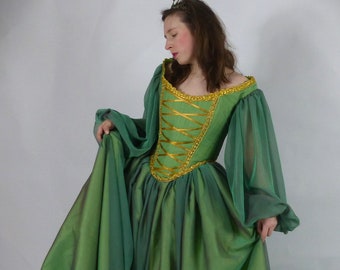 May include: A green and gold medieval style gown with long sleeves and a fitted bodice. The gown has a flowing skirt and is made of a sheer fabric.
