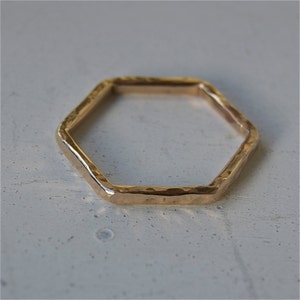May include: A gold hexagonal ring with a hammered finish.
