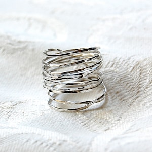 May include: A silver ring made of multiple thin bands twisted together. The bands are hammered and have a textured surface.