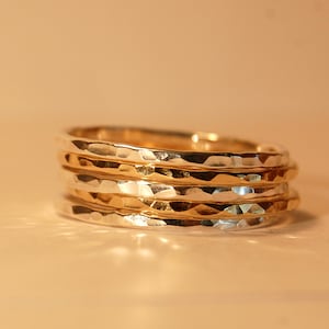 May include: A set of four hammered metal rings, two gold and two silver, stacked on top of each other.