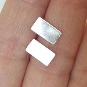 May include: Two silver rectangular earring studs.