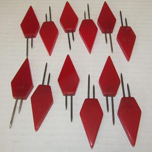 May include: Twelve red plastic diamond-shaped cocktail picks with two prongs on each pick.