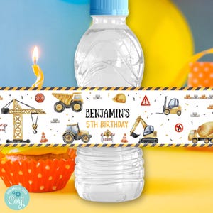 May include: A water bottle with a personalized label featuring construction vehicles and the text "Benjamin's 5th Birthday." The label has a yellow and black border and includes a crane, dump truck, and other construction equipment.