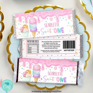 Op de afbeelding: Roze en blauwe chocolade reep verpakking met een kleurrijk ijshoorntje ontwerp. De verpakking zegt "SCARLETTE is Sweet ONE" en "HAPPY BIRTHDAY".