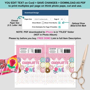 May include: A printable design template for a first birthday party, featuring a pink and white donut theme. The design includes text that says "Charlotte Sweet One" and a Ring Pop candy. Also included are a pair of gold scissors.