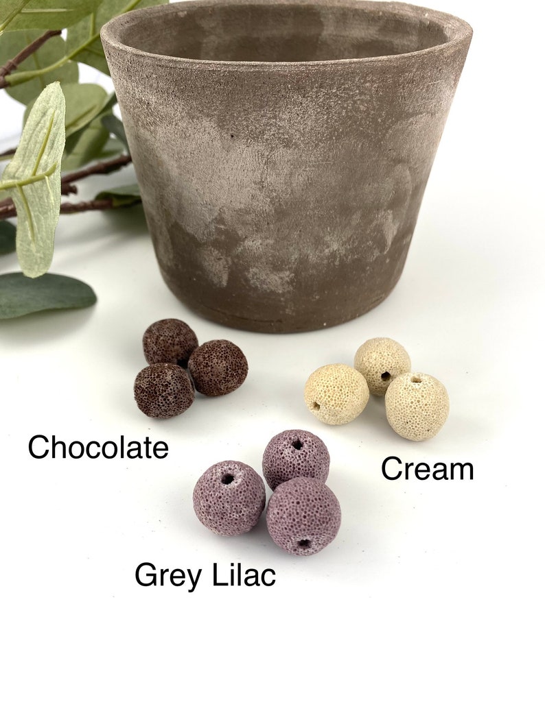 May include: Three sets of colorful ceramic beads in chocolate, cream, and grey lilac colors. The beads are round and have a textured surface.