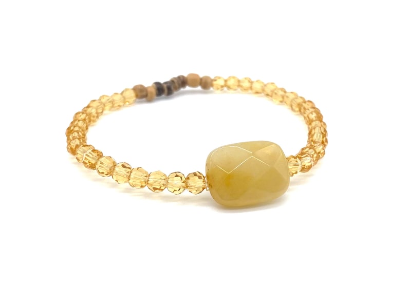 May include: A yellow crystal bead bracelet with a large, faceted, yellow gemstone charm.