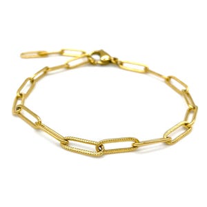 Könnte beinhalten: Ein goldfarbenes Kettenarmband mit strukturierter Oberfläche. Das Armband besteht aus miteinander verbundenen ovalen Gliedern.