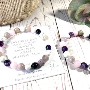 May include: A bracelet made with lavender jade, howlite, agate, and other stones. The bracelet is pink, white, and purple. The bracelet is handmade in Surrey. CRYSTAL JEWELLERY LAVENDER JADE CALM SUPPORT HOWLITE CALM PEACE AGATE DE-STRESS CALM stosa-design.com Handmade in Surrey