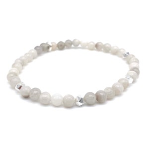 May include: A white and grey beaded bracelet with silver accents. The bracelet is made of small, round beads and has a delicate, minimalist design.