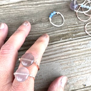 Könnte beinhalten: Zwei silberne Ringe mit klaren, runden, edelsteinartigen Perlen. Die Ringe werden an einem Finger getragen.