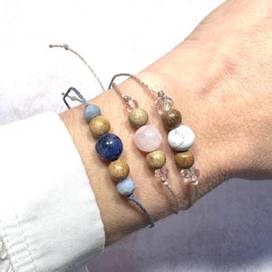 Puede incluir: Tres pulseras con cuentas de madera y detalles de piedras preciosas. Las pulseras est&aacute;n hechas con materiales naturales y presentan una piedra preciosa azul, rosa y blanca.