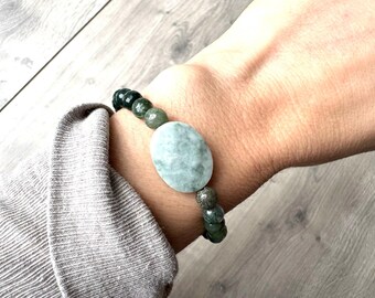 Puede incluir: Un brazalete de ágata verde y gris con un gran amuleto ovalado de ágata verde.