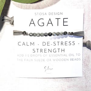 May include: A gray agate bracelet with a suede cord and a card that reads "STOSA DESIGN AGATE CALM - DE-STRESS - STRENGTH ADD 1-2 DROPS OF ESSENTIAL OIL TO THE FAUX SUEDE OR WOODEN BEADS"