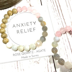 Peut inclure: Deux bracelets en perles de quartz rose, d'agate et de bois. Les bracelets sont sur un fond blanc avec une carte qui dit "Anxiété Relief" et "Rose Quartz - Agate Fabriqué à Surrey".