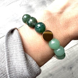Peut inclure: Un bracelet en perles vertes et dorées avec un charme doré. Le bracelet est composé de perles rondes en agate verte et d'un seul charme rond doré.