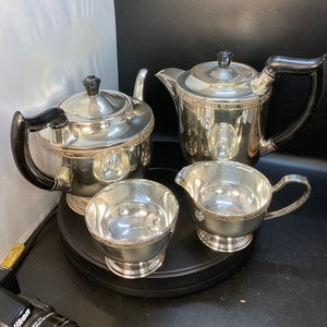 May include: A set of four silver tea service pieces, including a teapot, creamer, sugar bowl, and a small cup. The pieces are all highly polished and have a classic design.