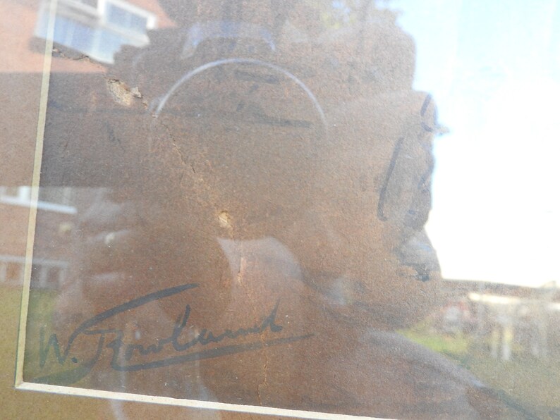 May include: A close-up of a framed artwork with a brown background and a black signature that reads "W.J.  Freund".