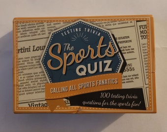 Könnte beinhalten: Eine Schachtel mit Trivia-Karten in Gelb, Orange und Schwarz. Die Schachtel zeigt ein blaues und weißes Achteck mit dem Text "The Sports Quiz" und "Calling All Sports Fanatics". Die Schachtel enthält auch den Text "100 Test-Trivia-Fragen für den Sportfan!"