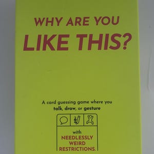 May include: A bright yellow card game box with the text "WHY ARE YOU LIKE THIS?" in large red letters. The box also includes the text "A card guessing game" and icons indicating the game is for 2+ players, ages 14+, and takes 15 minutes to play.