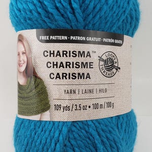 Może przedstawiać: Motka tealowej niebieskiej przędzy o nazwie "Charisma" firmy Loops & Threads. Etykieta zawiera napis "Wzór za darmo. Patron Gratuit. Patrón Gratis" oraz "109 jardów / 3,5 uncji. 100 m / 100 g."