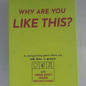 Peut inclure: Boîte de jeu de cartes jaune vif avec le texte "WHY ARE YOU LIKE THIS?" en grandes lettres rouges. La boîte comprend également le texte "A card guessing game where you talk, draw, or gesture" et "with NEEDLESSLY WEIRD RESTRICTIONS."