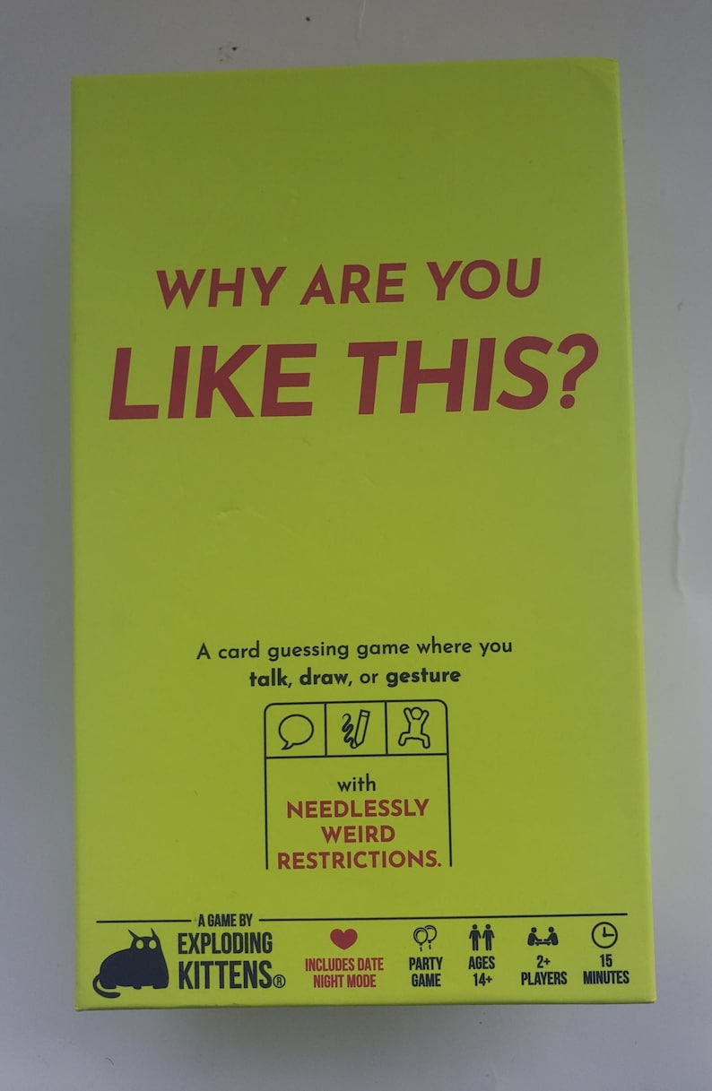 May include: A bright yellow card game box with the text "WHY ARE YOU LIKE THIS?" in large red letters. The box also includes the text "A card guessing game where you talk, draw, or gesture" and "with NEEDLESSLY WEIRD RESTRICTIONS."