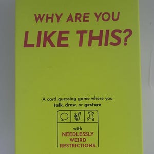 May include: A card game box with a bright yellow background and red text that reads "WHY ARE YOU LIKE THIS?". The box also includes the text "A card guessing game where you talk, draw, or gesture". The game is by Exploding Kittens.