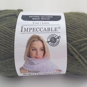 May include: A large ball of olive green yarn with a label that reads "Impeccable." The label features a woman wearing a lavender scarf. The yarn is 285 yards / 260 meters / 127.5 grams. The label also says "Pattern Included."