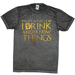 May include: A dark heather grey t-shirt with a gold graphic that reads "That's what I do I drink and I know things".