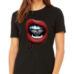 May include: Black t-shirt with a graphic of red lips and a diamond. The lips are glossy and dripping. The shirt has a crew neck design. The image is set against a white background.