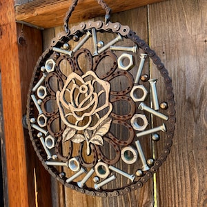 May include: A circular metal wall hanging with a rose design made from repurposed metal pieces, including nuts, bolts, and chain links.