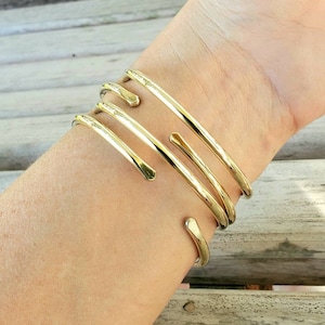 May include: A gold-toned metal bracelet with multiple bands wrapped around the wrist.