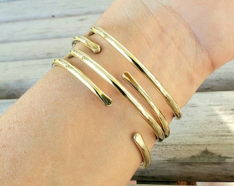May include: A gold-toned metal bracelet with multiple bands wrapped around the wrist.