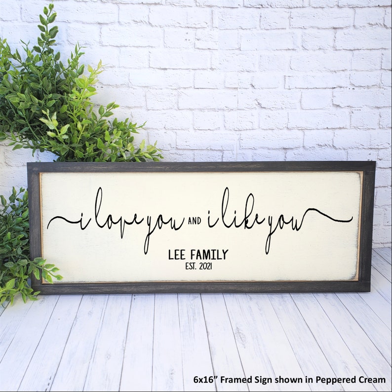 May include: A framed sign with the text "i love you and i like you" in black cursive script. Below the text is "LEE FAMILY EST. 2021". The sign is 6x16 inches and is shown in Peppered Cream.