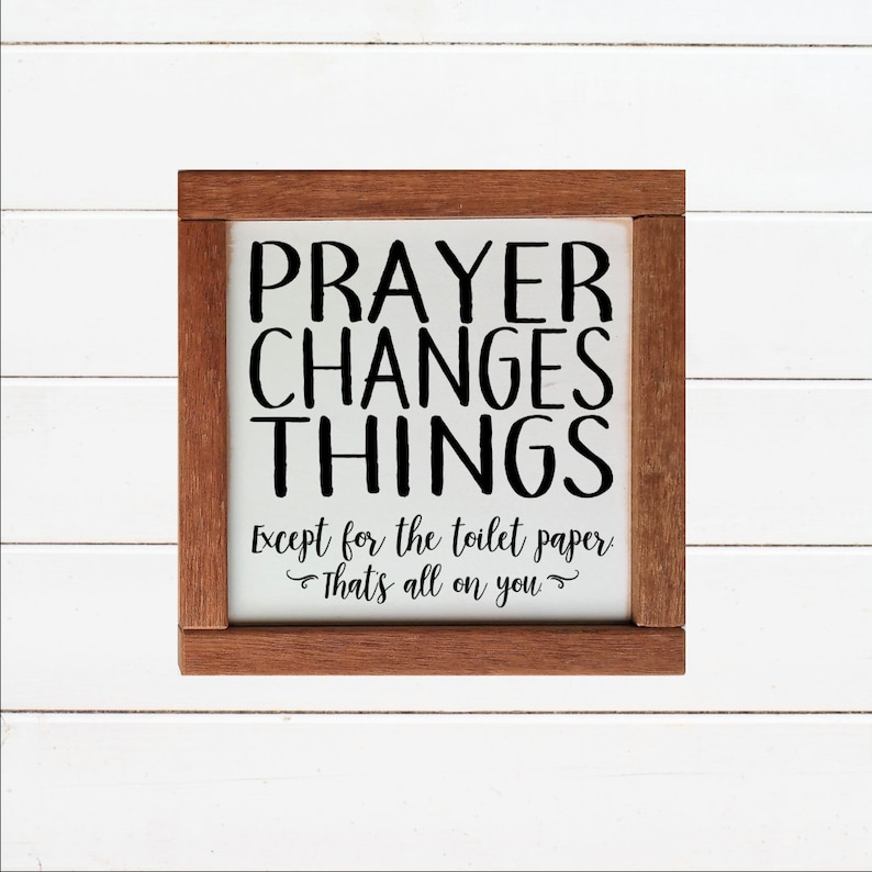 May include: A white wooden sign with a brown frame. The sign says "PRAYER CHANGES THINGS Except for the toilet paper That's all on you".