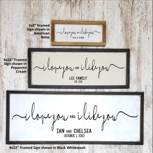 May include: Three framed wood signs with the text "i love you and i like you" in black script. The signs are shown in three different sizes: 3x8 inches, 6x16 inches, and 8x22 inches. The signs are shown in three different frame styles: American boho, peppered cream, and black whitewash.