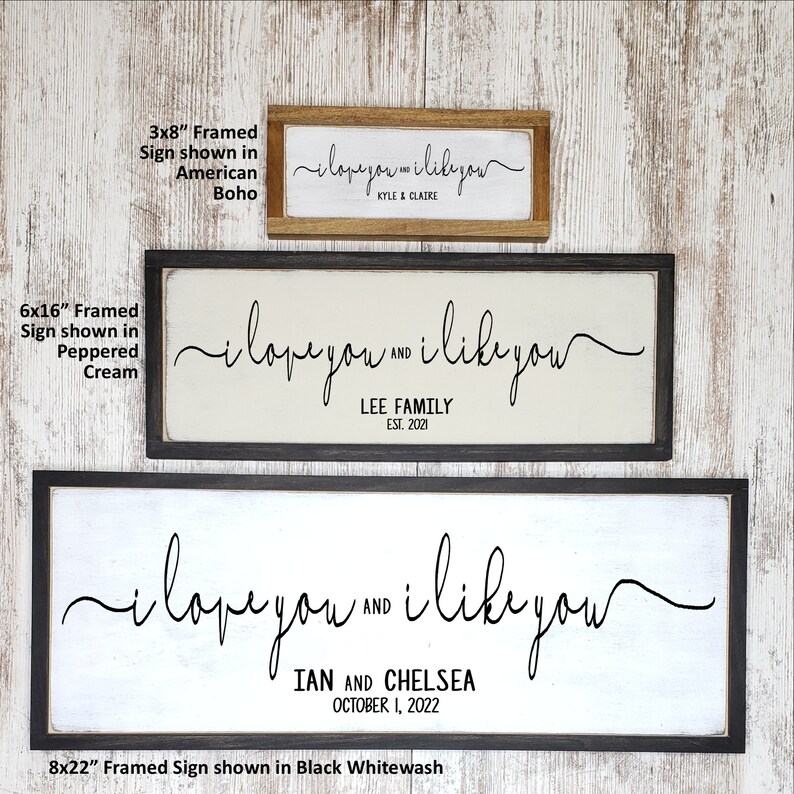 May include: Three framed wood signs with the text "i love you and i like you" in black script. The signs are shown in three different sizes: 3x8 inches, 6x16 inches, and 8x22 inches. The signs are shown in three different frame styles: American boho, peppered cream, and black whitewash.