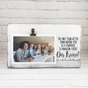 May include: White wooden picture frame with a clip to hold a photo. The frame has a black and white quote that reads "The only thing better than having you as a coworker is knowing you're Our Friend".