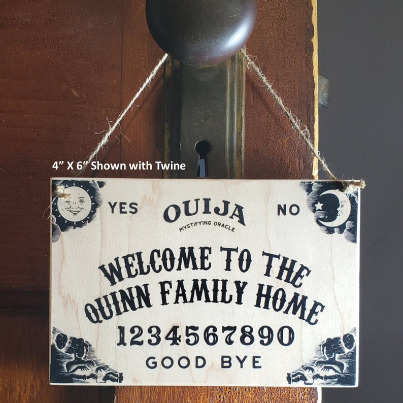 Pu&ograve; includere: Un cartello rettangolare in legno per la tavola Ouija, 10 cm x 15 cm, con la scritta "Welcome to the Quinn Family Home". Il cartello include i numeri 0-9, "Yes", "No" e "Good Bye". &Egrave; sospeso con dello spago.