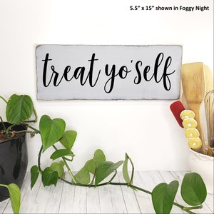 May include: A gray wooden sign with the text "treat yo'self" in black cursive lettering. The sign is 5.5 inches by 15 inches.