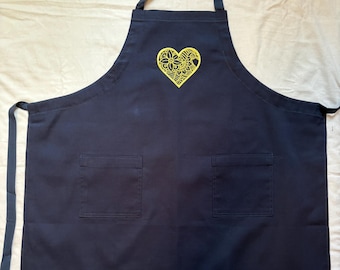 Embroidered aprons with a one piece strap fits around neck, goes through armhole gussets and ties in back.