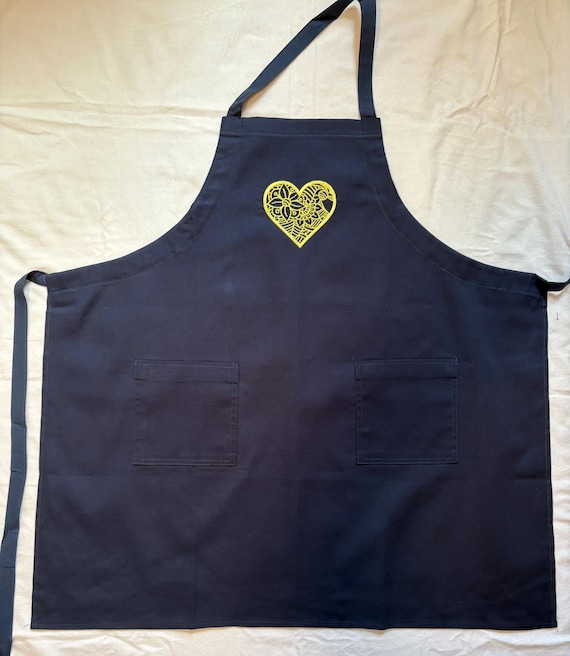Embroidered aprons with a one piece strap fits around neck, goes through armhole gussets and ties in back.