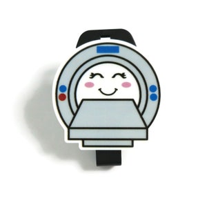May include: A white and gray cartoon MRI machine with a smiling face. The machine has blue and red buttons on the side.