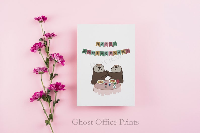 May include: A greeting card with two otters holding hands at a table with food and a rose. The card says "Happy Anniversary" with a banner above the otters.