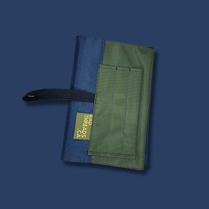 May include: A blue and green fabric roll-up case with a black strap and a gold label that reads "RAD THREADS .CA"