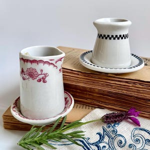 May include: A white ceramic mug with a black handle and the text "But First, Coffee" in a handwritten style. The mug is on a white surface. The mug is 4 inches tall.